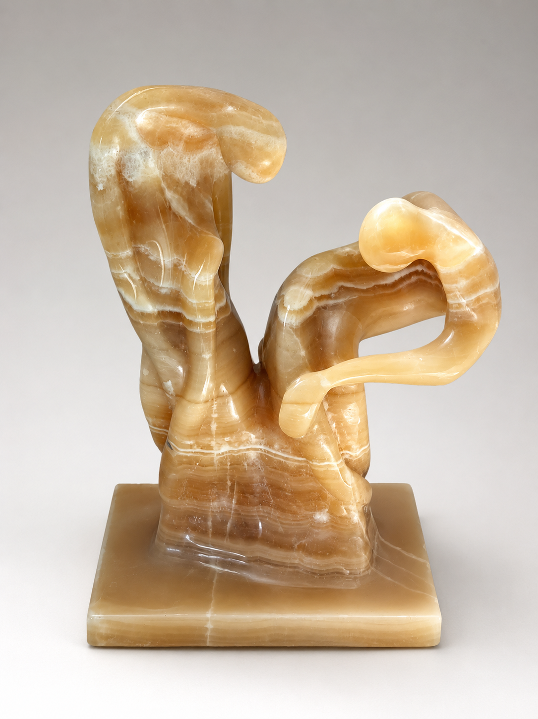 Abstract onyx stone sculpture with warm amber veining on a neutral background